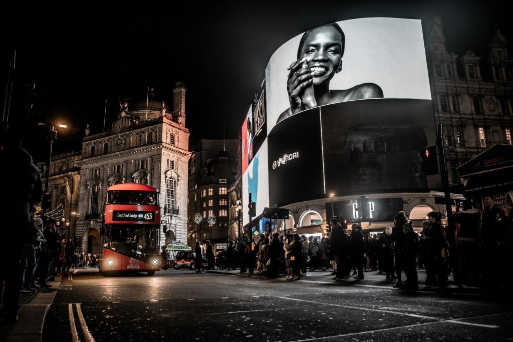 Vibrant city life at night in Piccadilly Circus, London with double-decker bus and illuminated billboards.